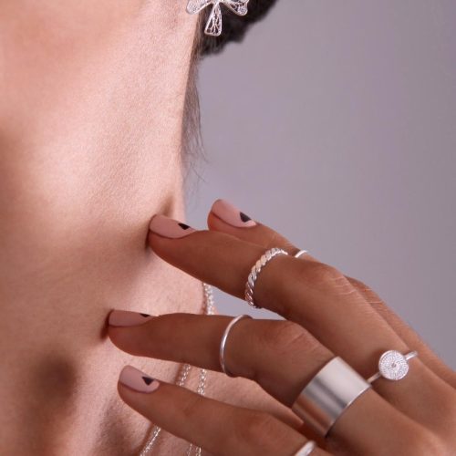 close-up-silver-earring-shape-filigree-clover-hand-with-silver-rings-touching